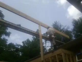 Carpenter setting a ridge beam over a new addition frame — Ice Dam Removal by Roofing Brothers in Blair