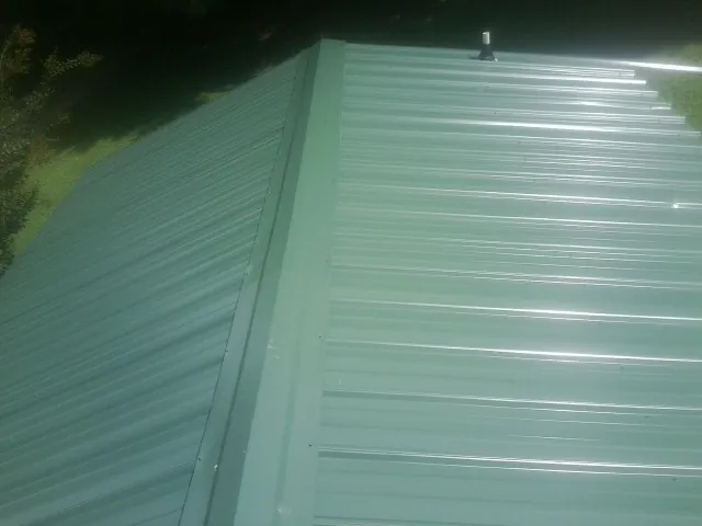 New green metal panels meeting at the ridge of a roof — Flat Roof Repair work by our crew in Blair