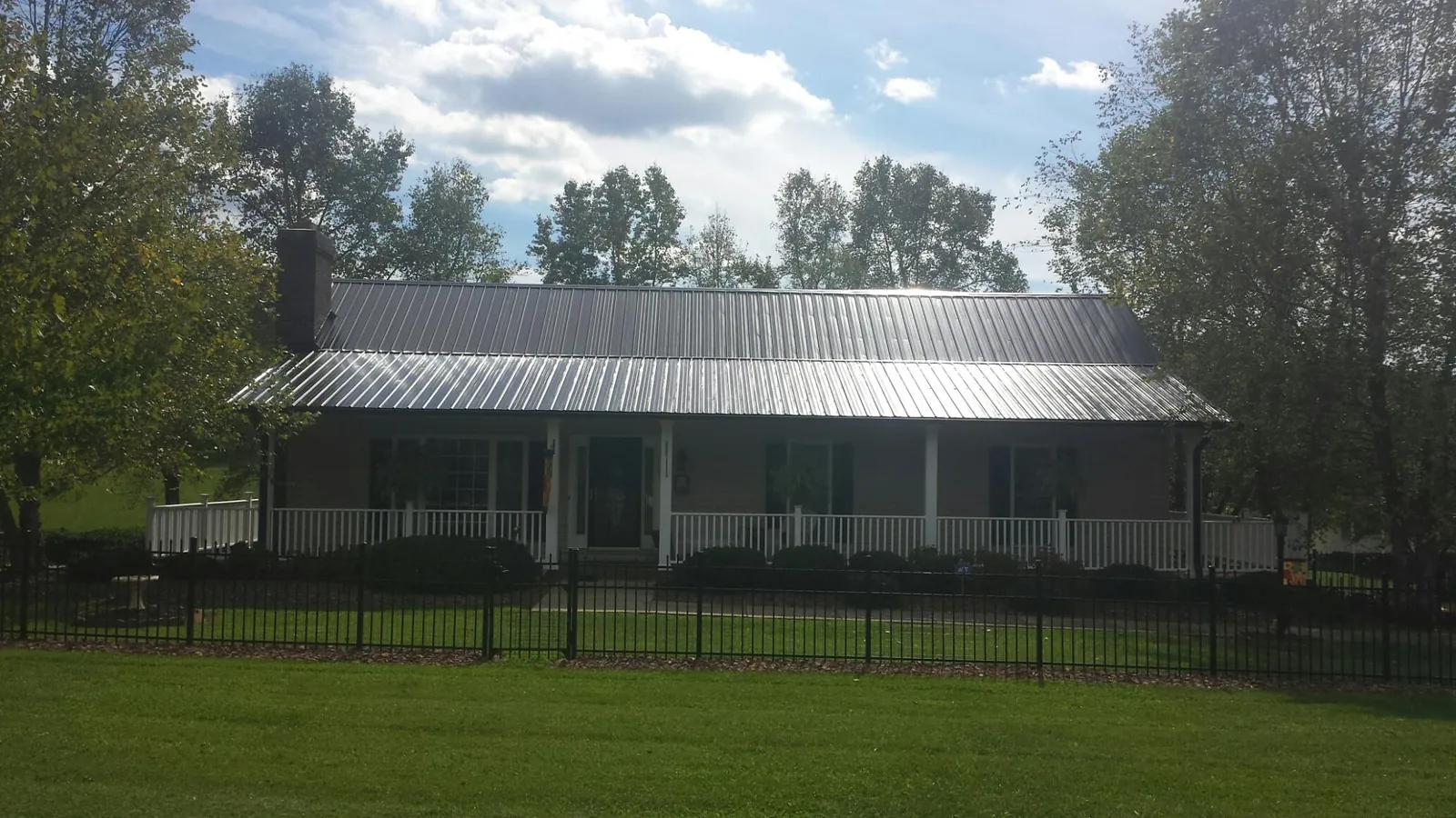 Gray metal roof on a brick ranch with a full width front porch — Gutter Guard Installation work by our crew in Blair